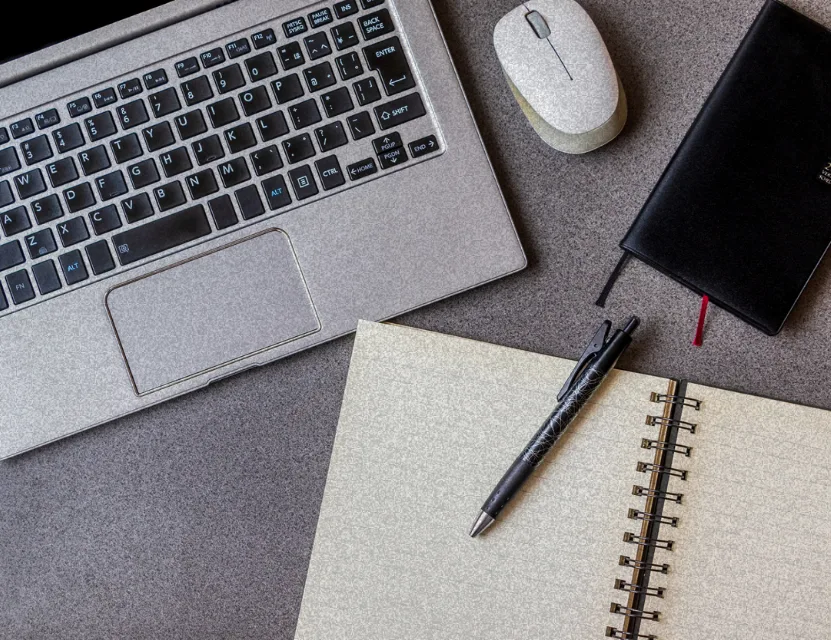 Notebook, caderno e caneta sobre uma mesa de trabalho