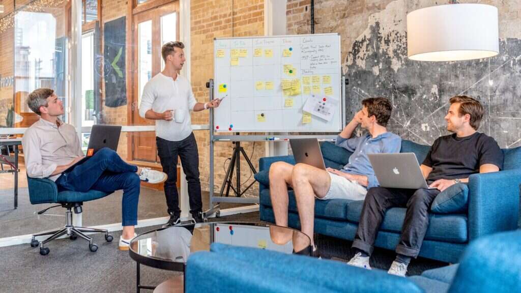 Equipe de marketing analisando um fluxo de trabalho em um quadro durante reunião