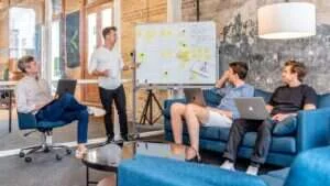 Equipe de marketing analisando um fluxo de trabalho em um quadro durante reunião
